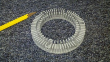 White plastic gear next to a yellow pencil